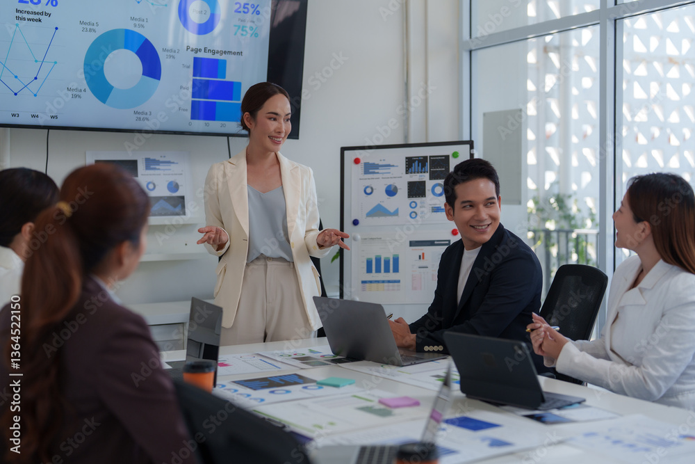Asian businesswoman leading a meeting in a modern office, presenting data and engaging with her team as charts and graphs display on a large screen and whiteboard